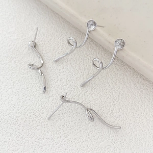 Macro shot of silver spiral geometric ribbon earring findings with pearl base settings