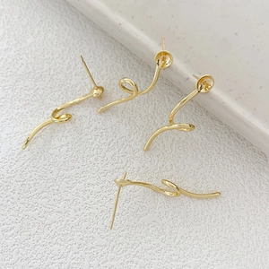 Detail of gold plated S-shaped spiral earrings parts with pearl cups for jewelry making