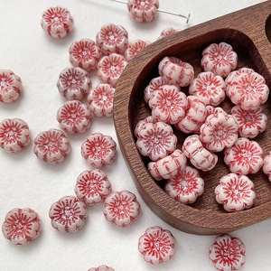 Detail of vintage double-sided flower glass beads in light pink with red glaze accents