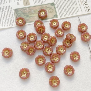 Macro view of handmade pink matte glass rose beads with golden floral stamens for DIY jewelry