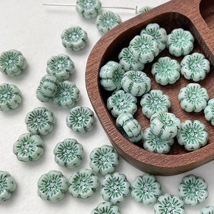 Detailed view of light green flower-shaped Czech glass beads for DIY jewelry making