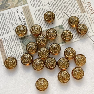 Macro detail of amber glass beads with gold rose carvings on vintage newspaper background