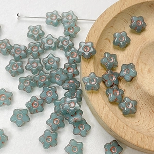 Macro shot of grey-blue star-shaped Czech glass beads with hand-painted bronze accents