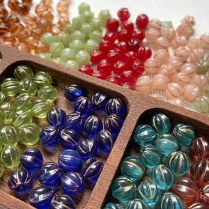 Macro detail of colorful Czech glass pumpkin beads with gold accents on a wooden tray
