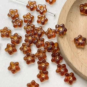 Macro view of amber glass flower beads on a wooden tray for DIY jewelry making