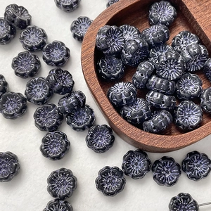 Macro view of vintage black flower Czech glass beads with purple luster for DIY jewelry