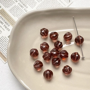 Detailed view of amber Czech glass pumpkin beads with gold-rimmed texture on a tray