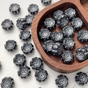 Macro detail of vintage black Czech glass flower beads with white rubbed texture for DIY jewelry