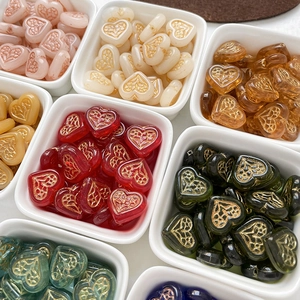 Macro shot of colorful heart-shaped lampwork glass beads with gold patterns in a ceramic bowl