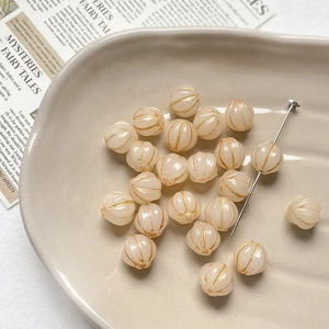Macro view of creamy white pumpkin glass beads with gold accents for DIY jewelry making