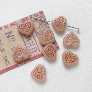 Detail of vintage heart-shaped glass beads with floral engravings for DIY jewelry making