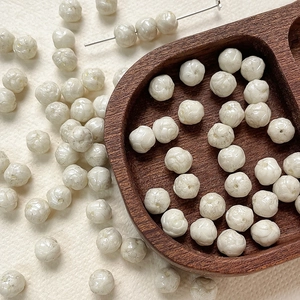Macro detail of white 8mm rose glass beads with embossed texture for DIY jewelry making