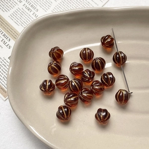 Macro detail of amber pumpkin glass beads with gold stripes for DIY jewelry making