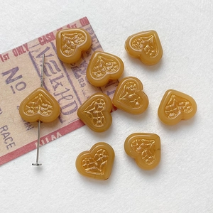 Macro shot of amber heart-shaped glass beads with embossed floral patterns for DIY jewelry