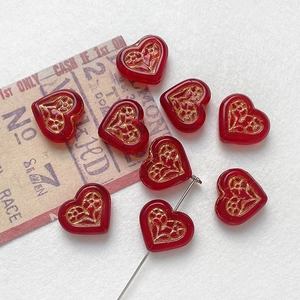 Macro shot of red glass heart beads with gold vintage floral patterns for DIY jewelry