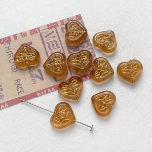 Macro detail of amber heart glass beads with gold floral pattern for DIY jewelry