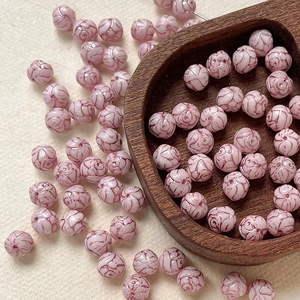 Detailed view of 8mm pink Czech glass beads with hand-painted rose texture for DIY crafts