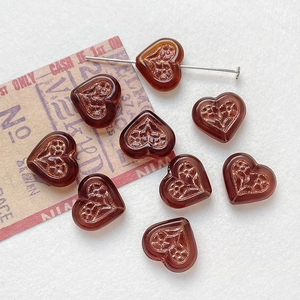 Macro shot of amber heart glass beads with embossed floral patterns for DIY jewelry