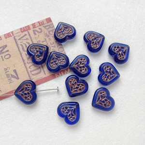 Macro detail of heart-shaped blue glass beads with gold-painted vintage floral patterns