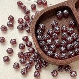 Macro detail of 8mm dark red Czech glass beads with vintage silver floral patterns
