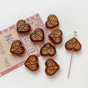 Macro shot of amber heart beads with gold floral engraving and bead threading detail