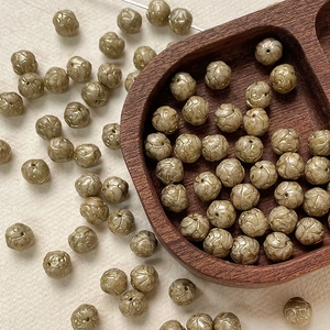 Macro view of 8mm champagne gold etched beads in a wooden heart tray for DIY jewelry