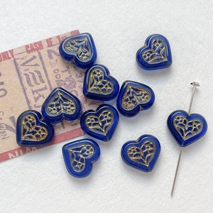 Macro shot of blue heart glass beads with gold floral patterns for DIY jewelry