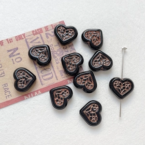 Macro view of black heart-shaped beads with vintage bronze texture for DIY jewelry making