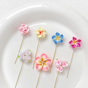 Épingles à fleurs artisanales en pâte polymère avec roses et frangipaniers sur plat