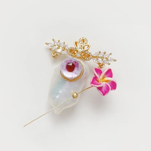 Broche en perle baroque avec ailes dorées, motif œil et détail de fleur de frangipanier