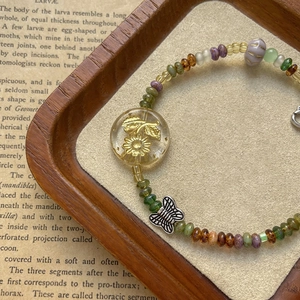 Vintage beaded bracelet with floral glass beads and silver butterfly pendant on book