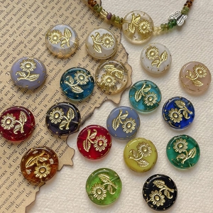 Macro shot of colorful retro Czech glass beads with golden floral relief on aged paper