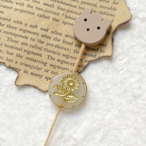 Macro shot of Czech glass bead with gold floral engraving and wooden bear detail
