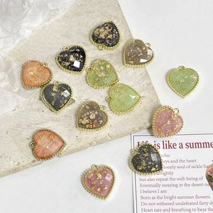 Macro detail of multi-color heart-shaped jewelry pendants with gold foil and metal frames