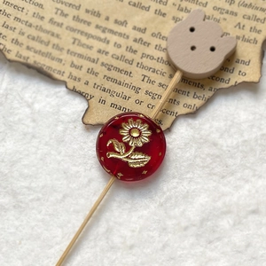 Detail of vintage double-sided etched red bead with gold sun flower and bear wood charm