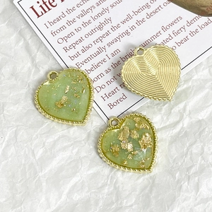 Detailed close-up of light green heart pendants with gold leaf foil and beaded edges