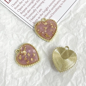 Macro detail of heart charm with pink gold foil inlay and gold textured back