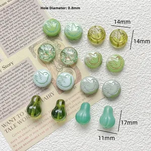 Macro detail of green Czech glass beads with gold bird engraving and water drop shapes