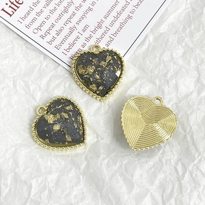 Macro detail of heart pendants with gold leaf inlay and textured metal backing