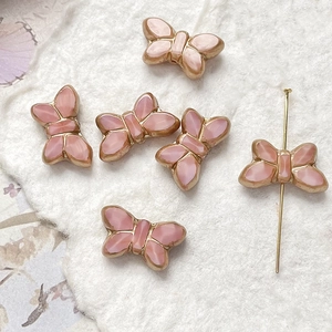 Macro detail of pink butterfly beads with gold edges showing horizontal hole placement