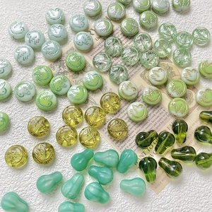 Detail of green glass beads with gold bird engravings for DIY jewelry making