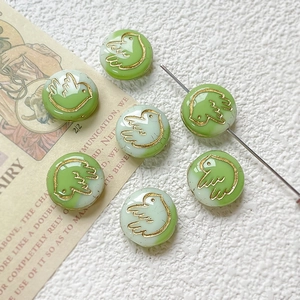 Macro shot of green and white glass beads with gold bird pattern for DIY jewelry