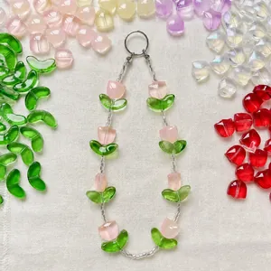 Pink tulip glass bead phone charm with green leaf accents on white linen fabric
