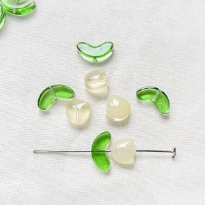 Detailed view of DIY tulip glass beads with green leaf and creamy yellow petal charms