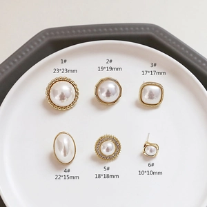 Detail view of 925 silver pearl stud earrings with gold frames in various geometric shapes