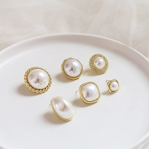 Detailed view of French vintage style faux pearl earrings with golden frames on a ceramic plate