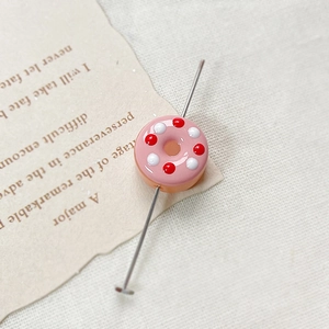 Detail of pink donut-shaped resin bead with colorful sprinkles for DIY jewelry making