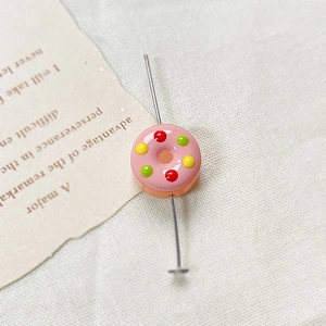 Macro shot of pink donut glass bead with colorful sprinkles for DIY jewelry making
