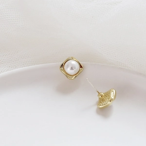 Macro view of square gold stud earrings with white pearls and wave edge detail