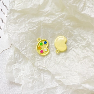 Macro detail of yellow alloy palette pendant for DIY jewelry making and bracelet design
